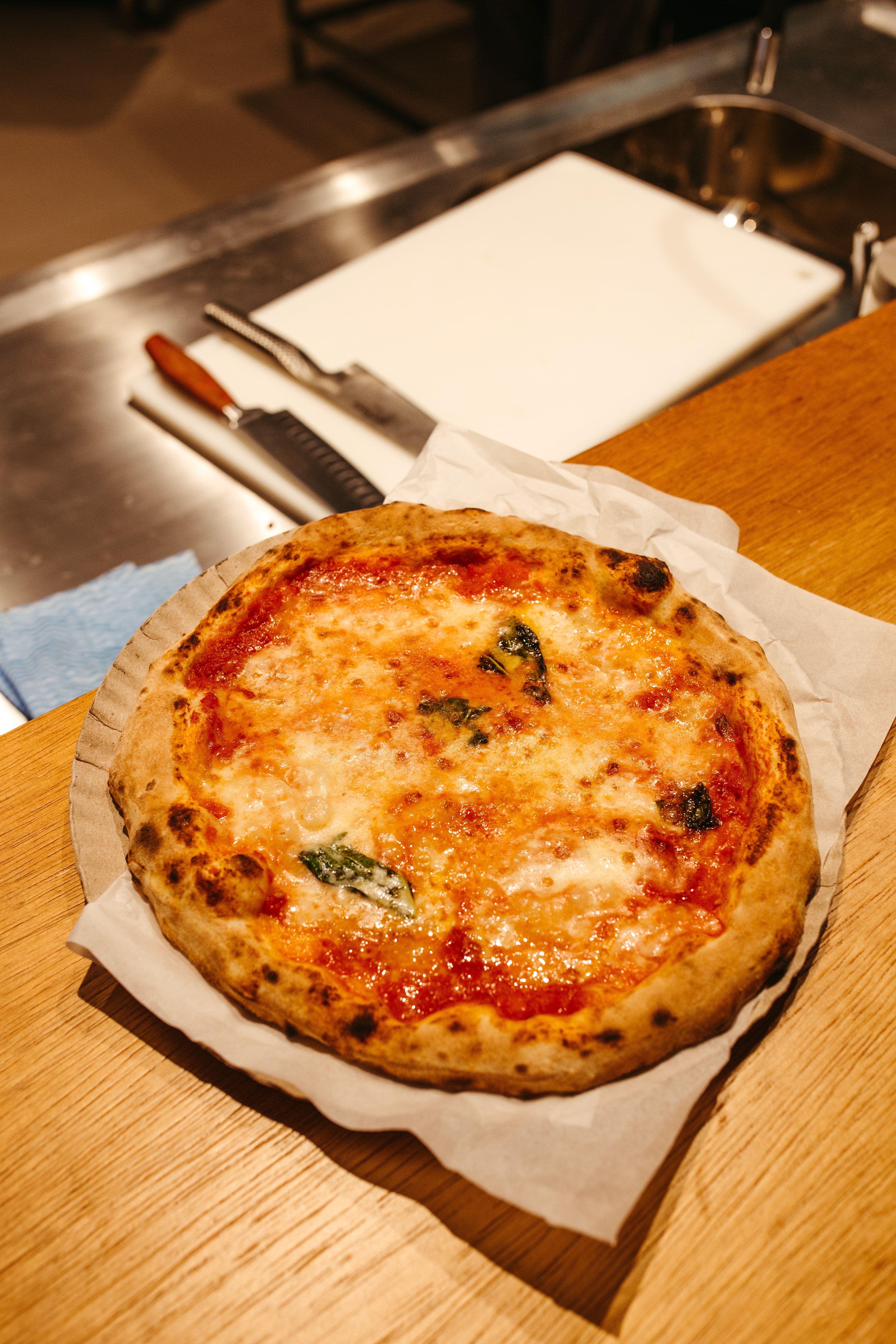 A wood-fired Neapolitan pizza with a leopard-charred crust, tomato, mozzarella and fresh basil
